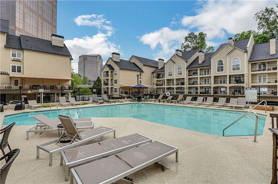Outdoor swimming pool area with surrounding multi-story buildings.