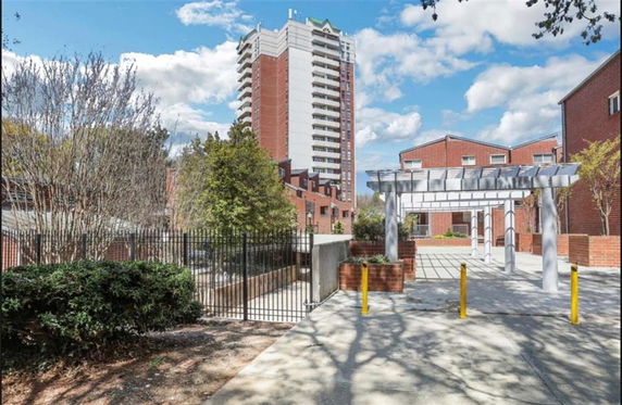 Front view of a multi-story building with red brick exterior and adjacent low-rise structures.