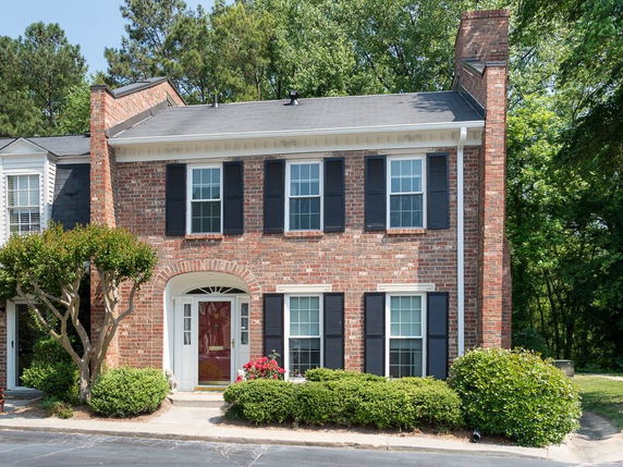 Front view of a two-story brick townhouse with black shutters.