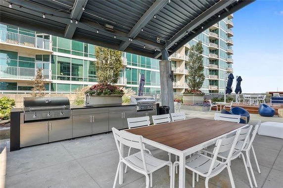 Rooftop area with a dining table, seating, and a built-in grill under a canopy.