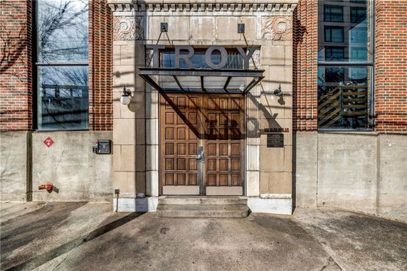 Front view of a building entrance with large wooden doors and brick exterior.