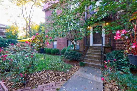 Front view of a multi-story brick building with stairs leading to the entrance.