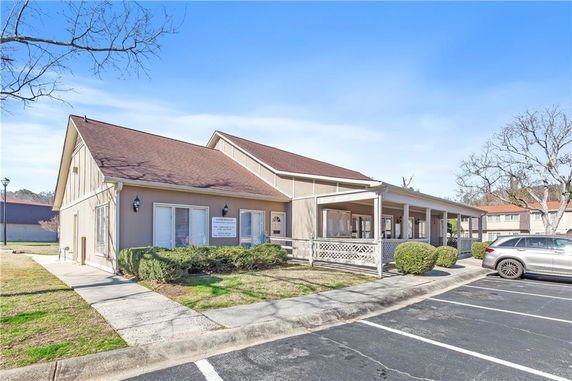 Front view of a single-story building with a porch and parking area.