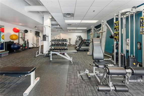 Indoor gym area with various exercise equipment and weights.