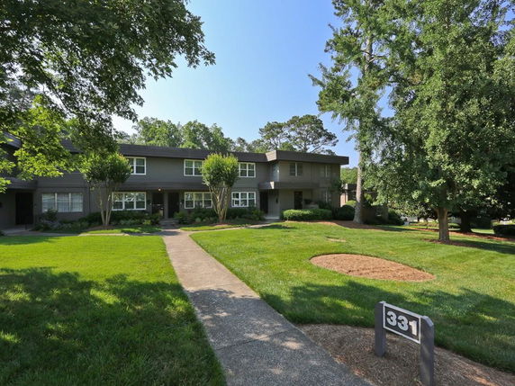 Front view of a two-story residential building with a lawn and path leading to the entrance.