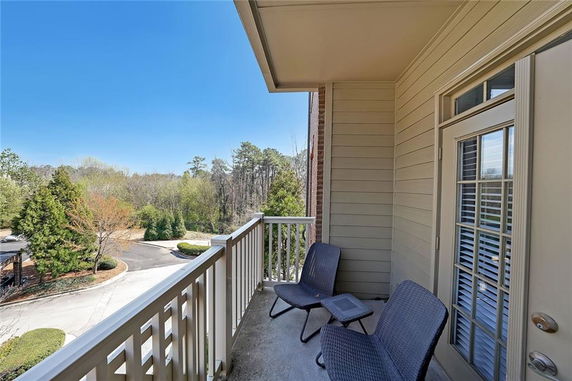 Balcony with chairs overlooking trees and road.