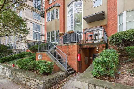 Front view of a multi-story brick building with a staircase leading to a terrace.