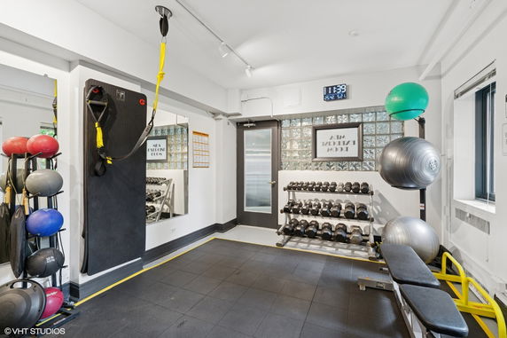 Indoor gym area with exercise equipment including weights, kettlebells, and a bench.