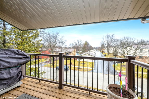 View from a balcony overlooking a suburban street with houses and trees.