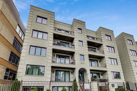 Front view of a multi-story apartment building with balconies and modern design.
