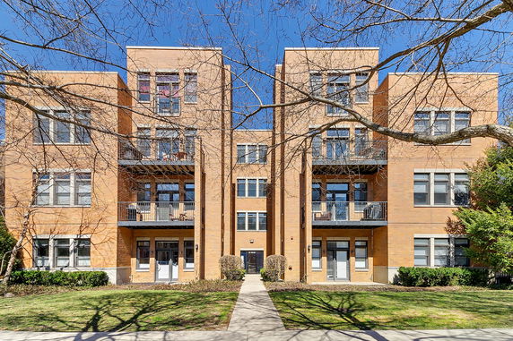 Front view of a multi-story brick apartment building with balconies.