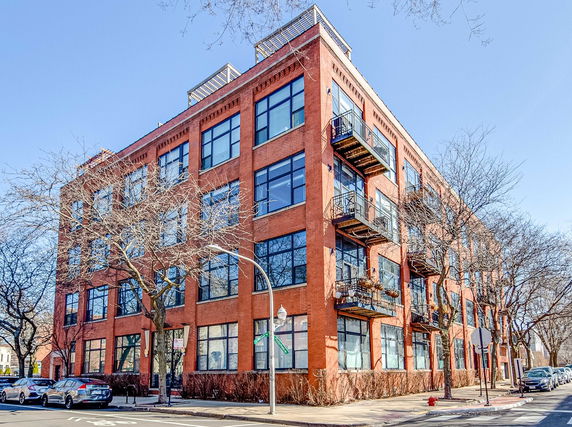 Front view of a multi-story brick building with large windows and balconies.