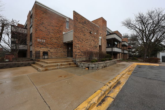 Front view of a multi-story brick apartment building with stair entry.
