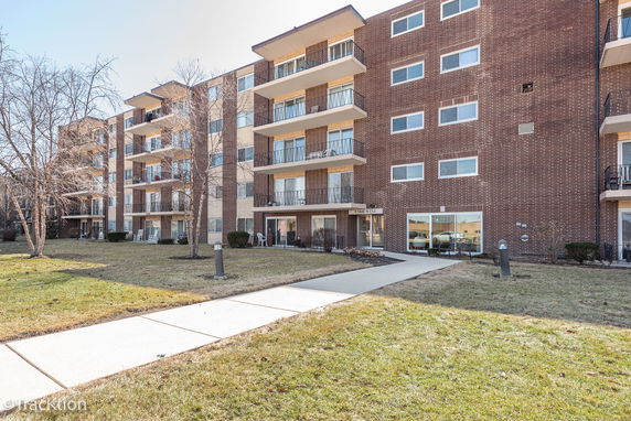 Front view of a multi-story brick apartment building with balconies.