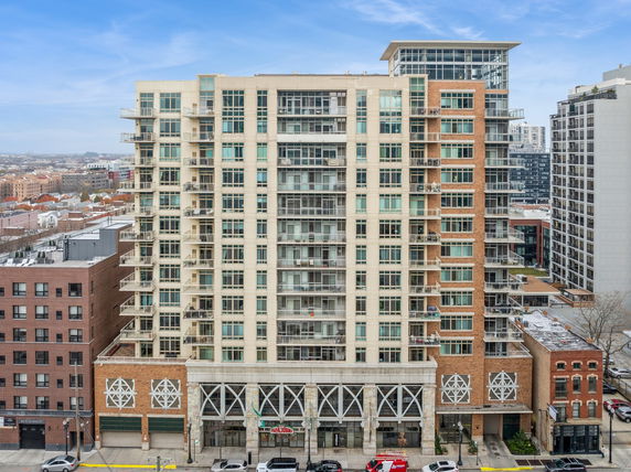 Front view of a multi-story building with numerous balconies and large windows.
