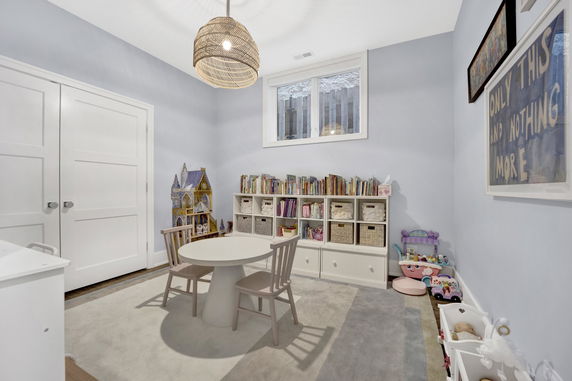 A room designed for children's activities with a small table, chairs, bookshelves, and toys for play.