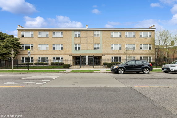 Front view of a three-story apartment building with a gated entrance.