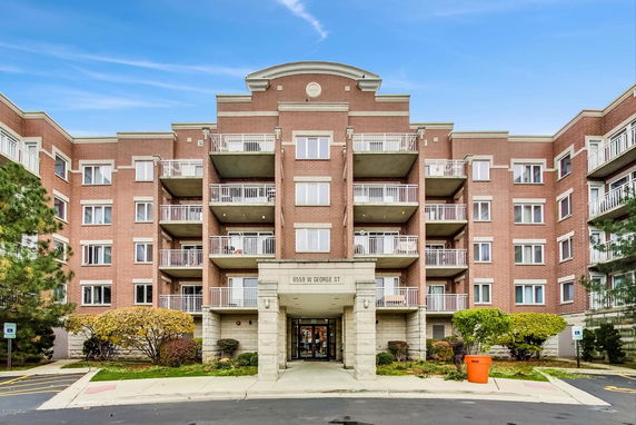 Front view of a multi-story apartment building with brick facade and multiple balconies.