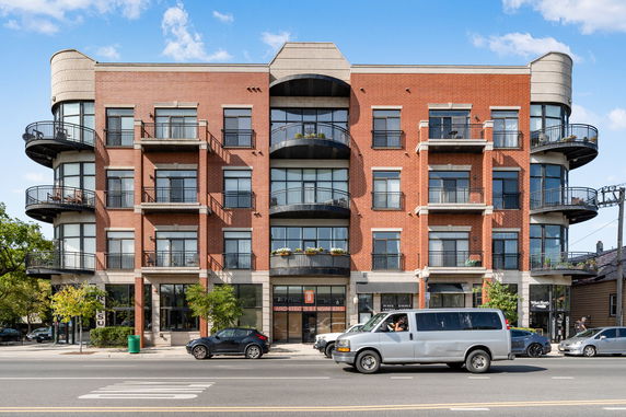 Front view of a multi-story brick building with balconies and large windows.
