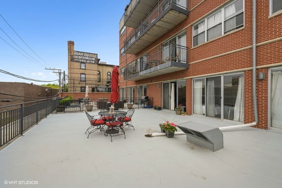 Rooftop area with seating and balconies on a multi-story brick building.