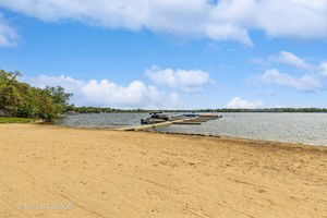 View of a sandy beach with a dock extending into the water.
