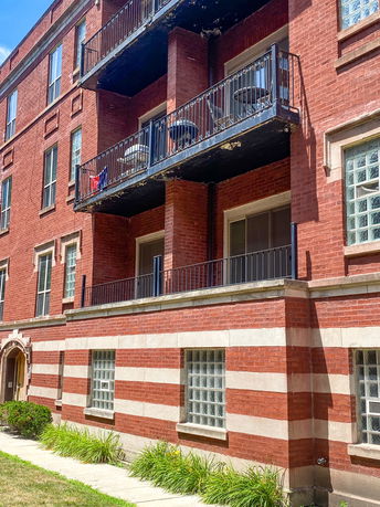 Front view of a multi-story brick apartment building with balconies.