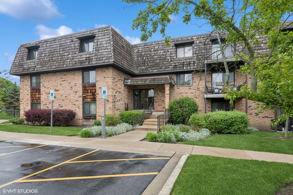 Front view of a multi-story brick building with a distinct shingled roof.