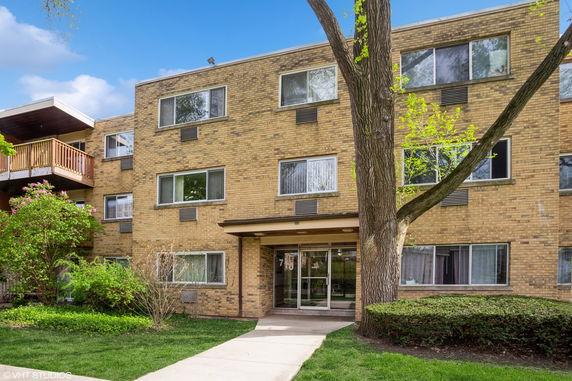Front view of a brick apartment building with multiple windows and a main entrance.