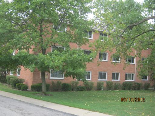 Front view of a three-story brick building surrounded by trees.