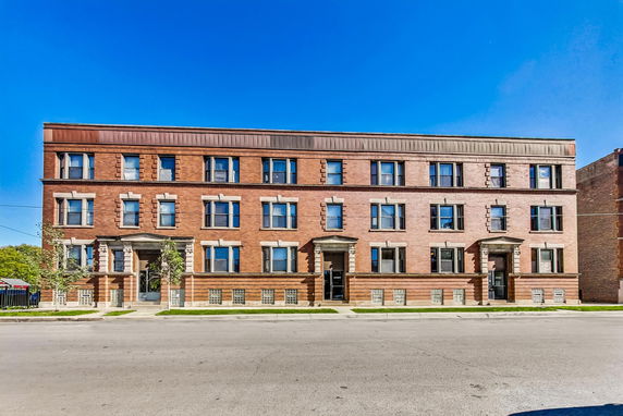 Front view of a three-story brick apartment building with multiple windows.