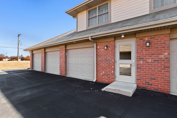 Front view of a building with multiple garage doors and a side entrance.