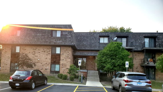 Front view of a multi-story brick building with a shingled roof and multiple balconies.