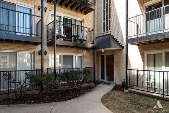 Front view of a multi-story apartment building with balconies and a pathway leading to the entrance.