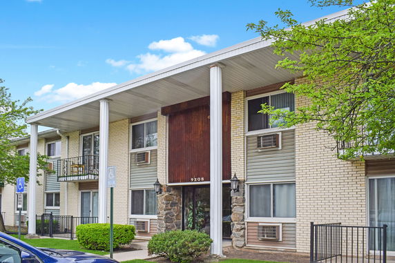 Front view of a multi-story residential building with balconies and brick facade.