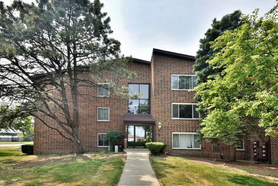 Front view of a multi-story brick building with large windows.