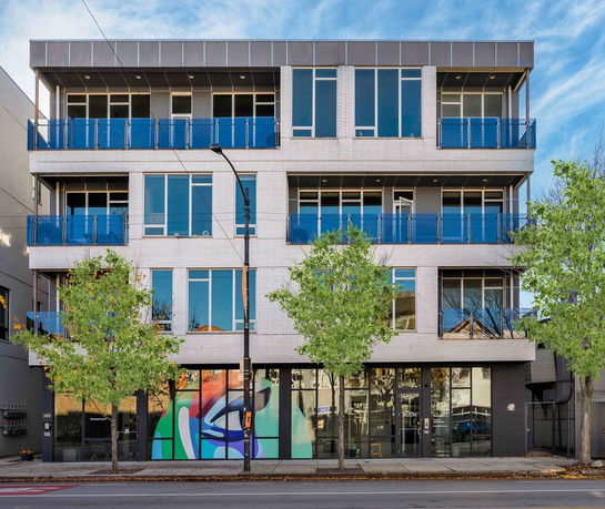 Front view of a modern multi-story building with large windows and balconies.