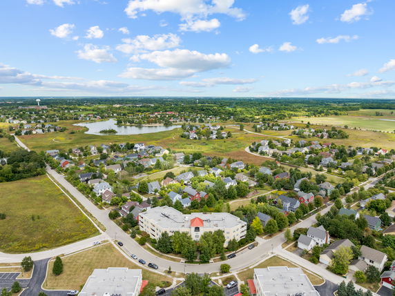 Panoramic view of a suburban neighborhood with houses, roads, and a lake in the background.