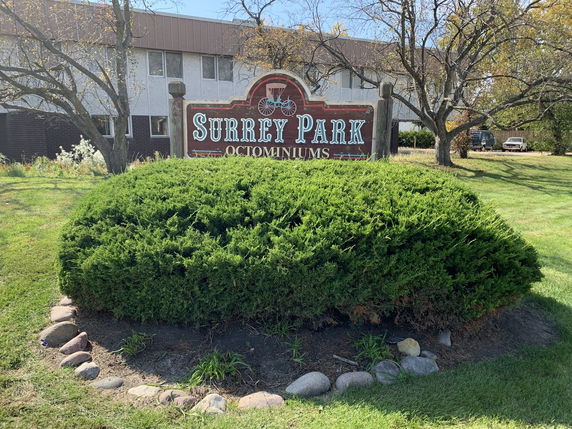 Front view of a residential building with a large sign reading 'Surrey Park Condominiums.'