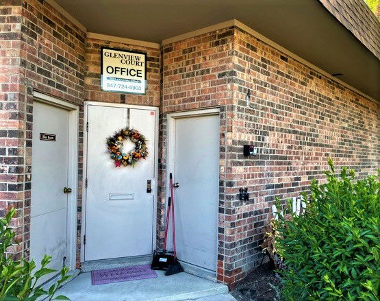Brick exterior of a building with office entrance and a holiday wreath on the main door.
