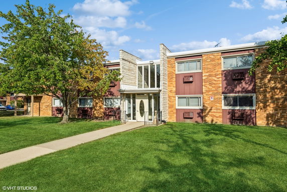 Front view of a two-story brick building with large windows.