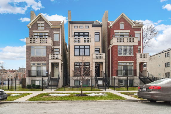 Front view of three adjacent multi-story houses with brick facades.