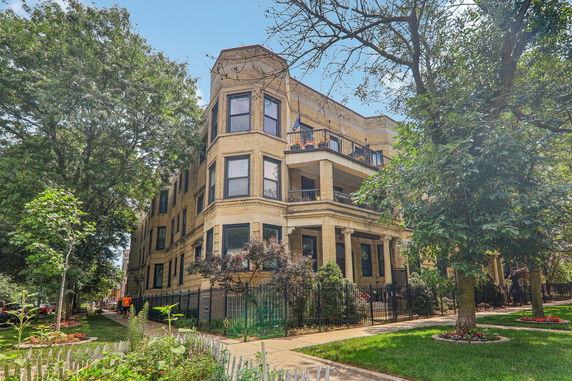 Front view of a multi-story apartment building with balconies and large windows.