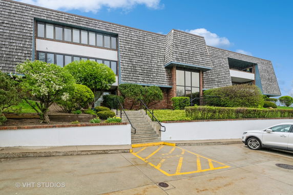 Front view of a multi-story building with a distinctive roof and large windows.