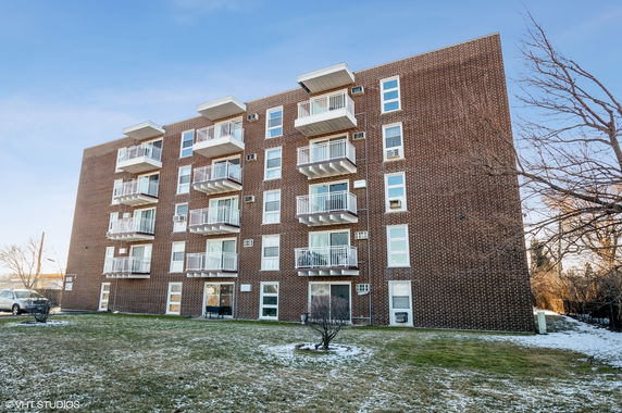Front view of a multi-story brick apartment building with balconies.