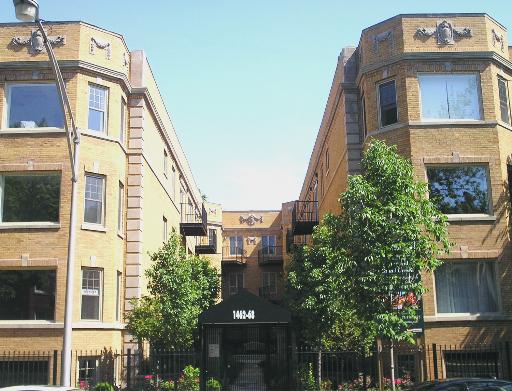 Front view of a multi-story brick apartment building with bay windows.