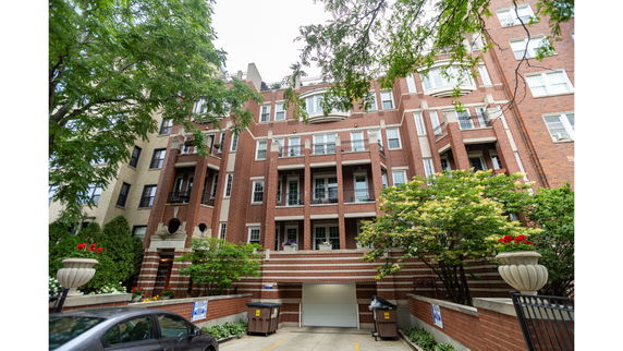 Front view of a multi-story brick apartment building with balconies.