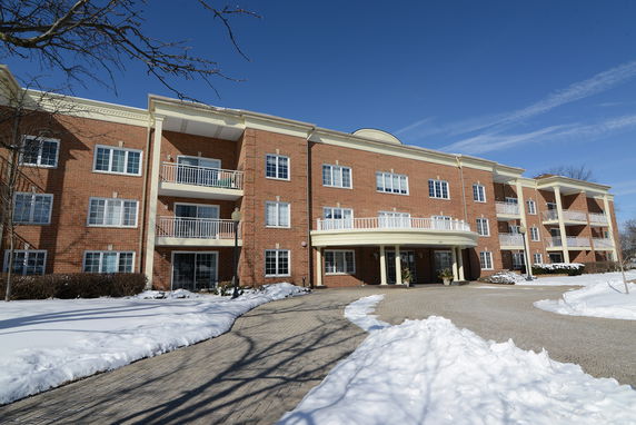 Front view of a multi-story brick building with balconies and a snowy pathway.