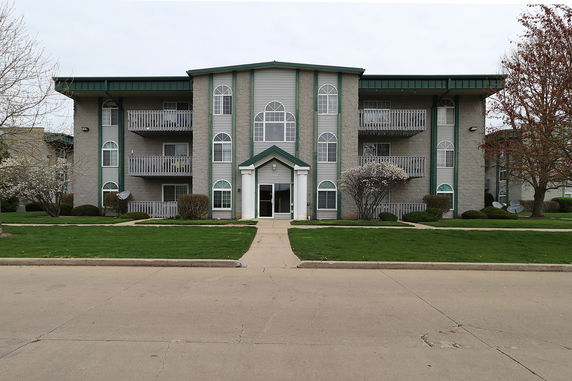 Front view of a multi-story apartment building with balconies and arched windows.