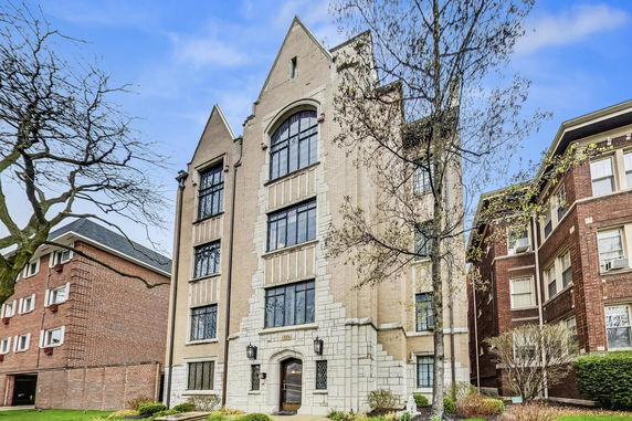 Front view of a multi-story residential building with intricate brickwork and large windows.