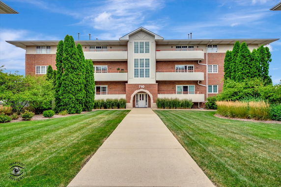 Front view of a three-story brick building with a central entrance and balconies.